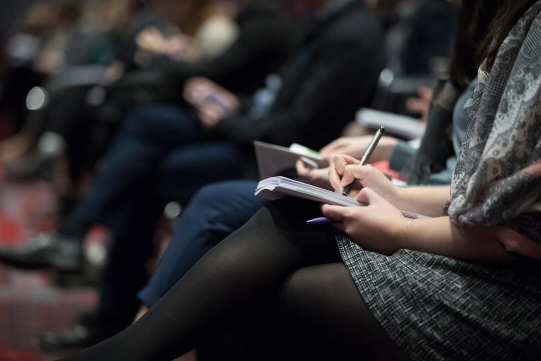 Photo by The Climate Reality Project selective focus photography of people sitting on chairs while writing on notebooks